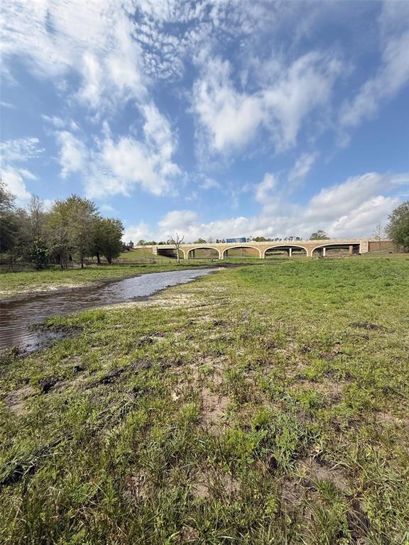 A grassy field with a small stream leads toward a multi-arched concrete bridge — 3330 PLYMOUTH SORRENTO ROAD, APOPKA, FL