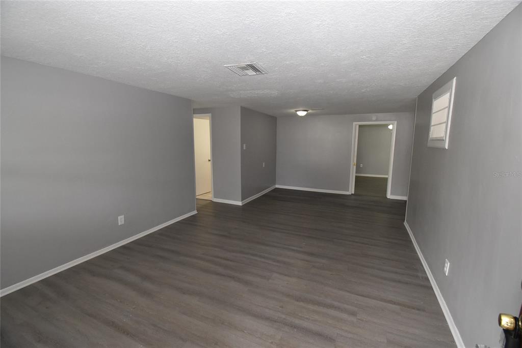 An empty room with gray walls, dark wood-look flooring, and two doorways — 11025 PICKERING LANE, PORT RICHEY, FL