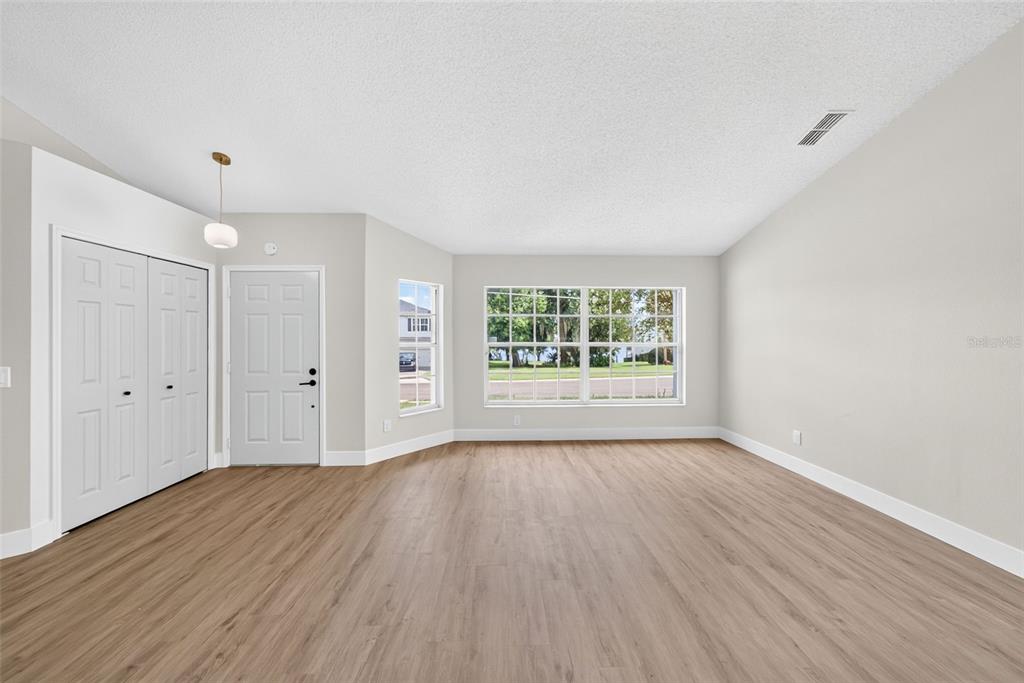 An empty dining area features wood-look flooring, a modern light fixture, and a kitchen pass-through — 294 LAKE DOE BOULEVARD, APOPKA, FL