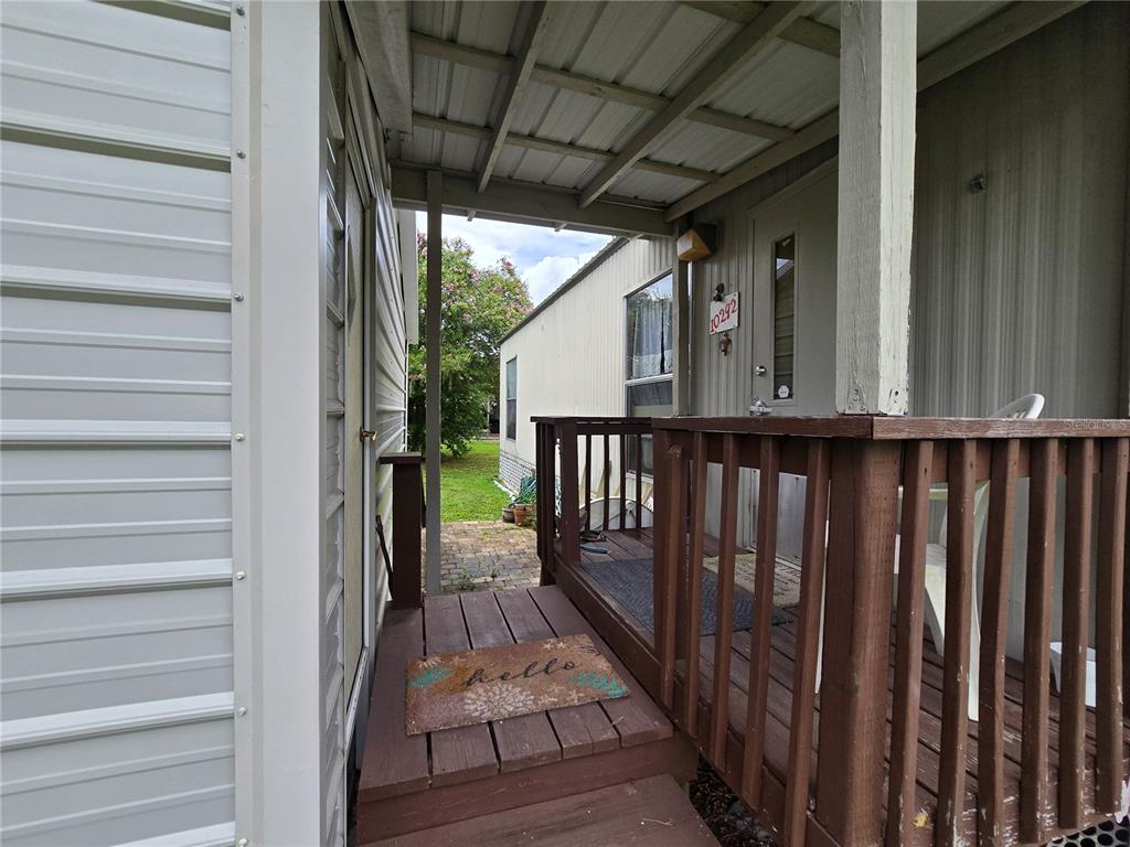 A covered wooden porch connects two mobile home structures with a hello doormat — 10292 E PIKE DRIVE, INVERNESS, FL