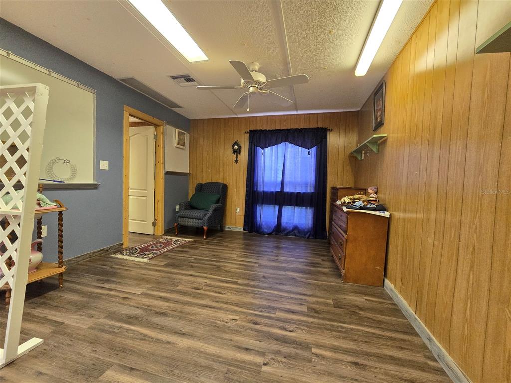 A room with wood-paneled walls, blue accent paint, wood-look flooring, and a ceiling fan — 10292 E PIKE DRIVE, INVERNESS, FL