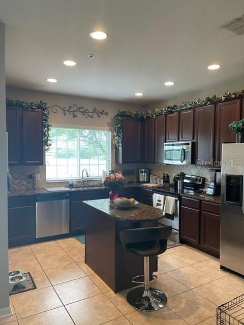 A kitchen features dark wood cabinets, granite countertops, stainless steel appliances, and a central island — 2526 PASSAMONTE DRIVE UNIT 10F, WINTER PARK, FL