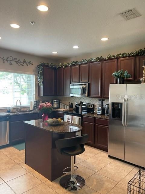 A kitchen features dark wood cabinets, granite countertops, a center island, and stainless steel appliances — 2526 PASSAMONTE DRIVE UNIT 10F, WINTER PARK, FL