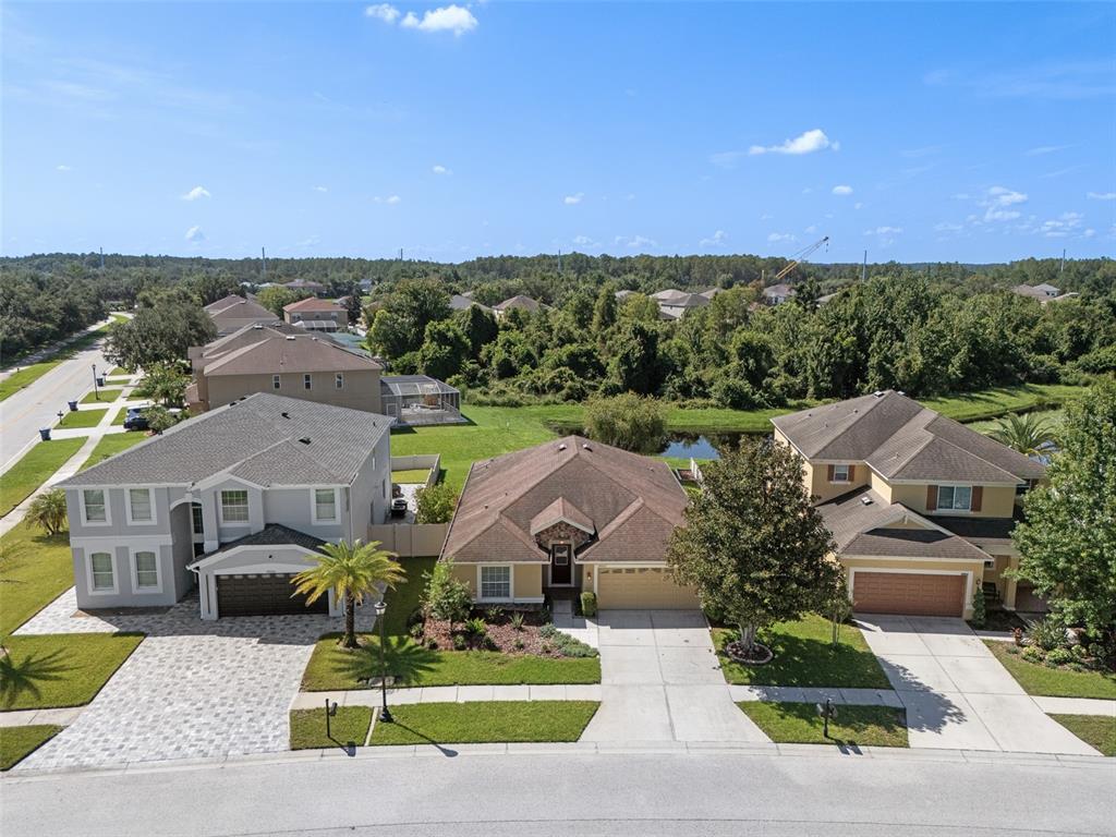 An aerial view shows three suburban houses with driveways and lawns along a paved street — 19002 NARIMORE DRIVE, LAND O LAKES, FL