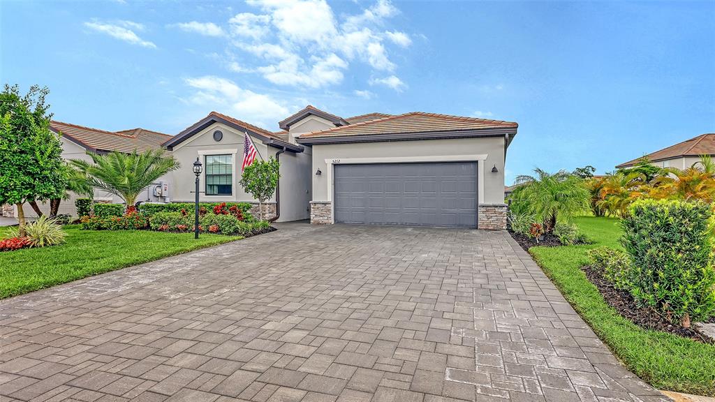 A single-story house with a gray garage, paver driveway, and landscaped front yard — 5212 MARINA BASIN COURT, BRADENTON, FL