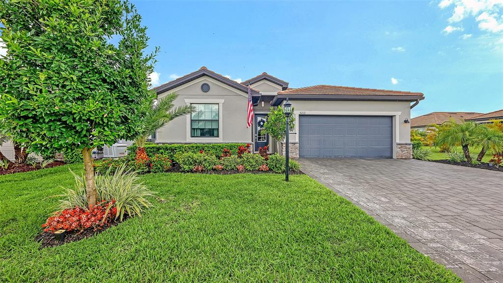 A single-story house with a gray garage, a paved driveway, and a landscaped front yard — 5212 MARINA BASIN COURT, BRADENTON, FL
