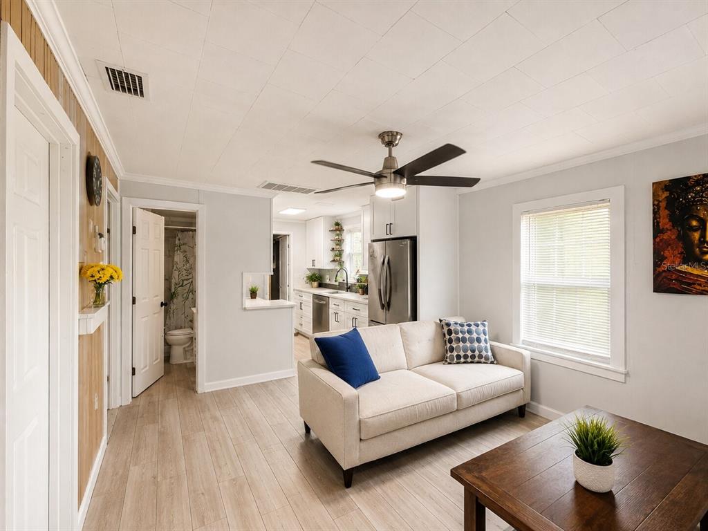 A kitchen features white cabinets, stainless steel appliances, a tiled backsplash, and light wood flooring — 217 50TH TER N, ST PETERSBURG, FL