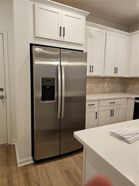 A kitchen features white cabinets, stainless steel appliances, quartz countertops, and wood-look flooring — 11459 SUNSAIL AVENUE, ORLANDO, FL