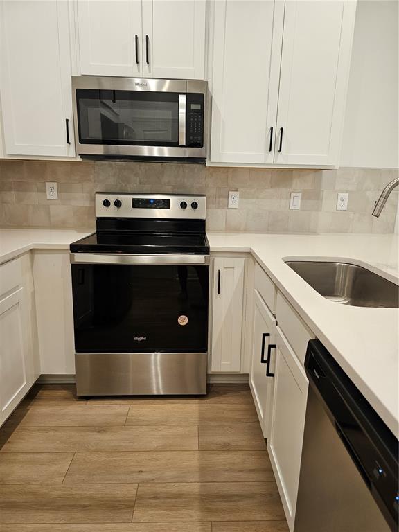 A modern kitchen features white cabinets, quartz countertops, a kitchen island, and wood-look flooring — 11459 SUNSAIL AVENUE, ORLANDO, FL