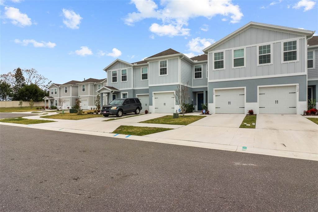A row of two-story townhomes with light blue siding, white trim, and attached garages — 3138 VICTORIA INLET DRIVE, HOLIDAY, FL