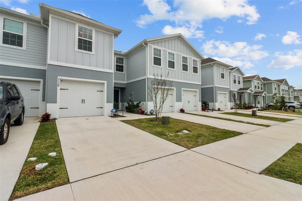 A row of two-story townhouses with attached garages and concrete driveways under a blue sky — 3138 VICTORIA INLET DRIVE, HOLIDAY, FL