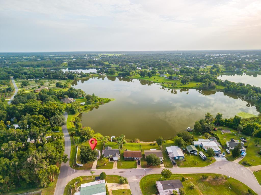 An aerial view shows a house marked with a pin beside a large lake — 57 CAYMAN CIRCLE, UMATILLA, FL