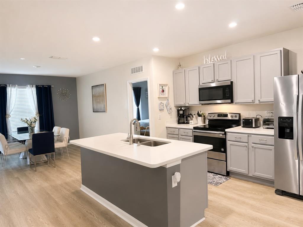 A kitchen with a central island, grey cabinets, and an adjacent dining area — 3653 SCARLET OAK DRIVE, ST CLOUD, FL
