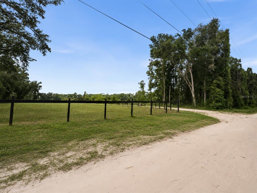An aerial view shows a large, cleared rectangular plot of land surrounded by dense forest — 17807 SW 83RD AVENUE, ARCHER, FL
