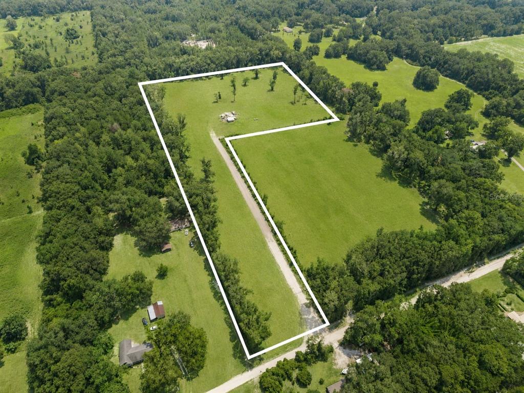 An aerial view shows a large, L-shaped plot of cleared land surrounded by trees — 17807 SW 83RD AVENUE, ARCHER, FL