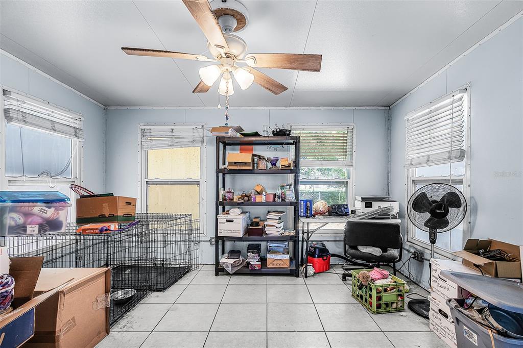 A room with tiled floors, a ceiling fan, windows with blinds, and various storage items — 11337 SW PINE AVENUE, ARCADIA, FL