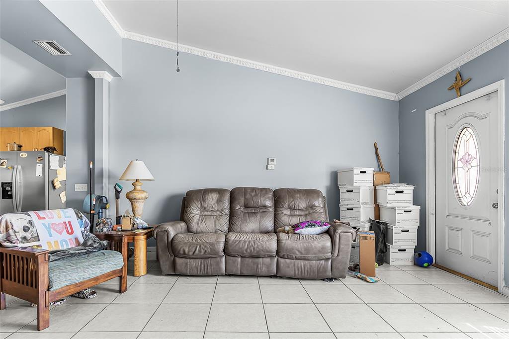 A living room features a grey sofa, a wooden armchair, and white tiled flooring — 11337 SW PINE AVENUE, ARCADIA, FL