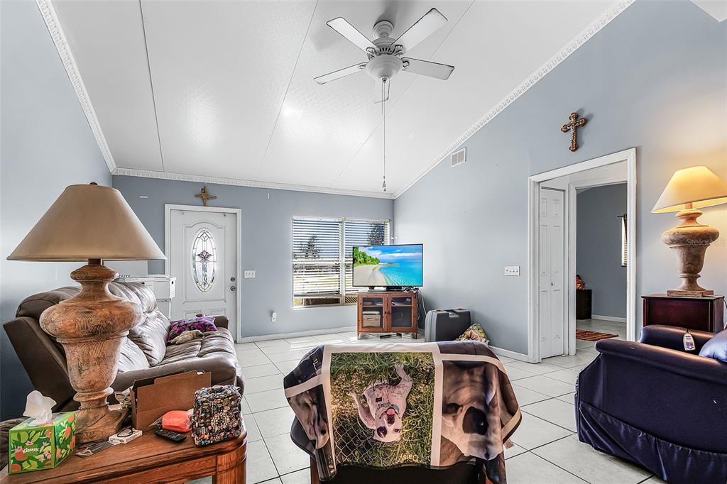 A living room features light blue walls, tile flooring, a ceiling fan, and a television — 11337 SW PINE AVENUE, ARCADIA, FL