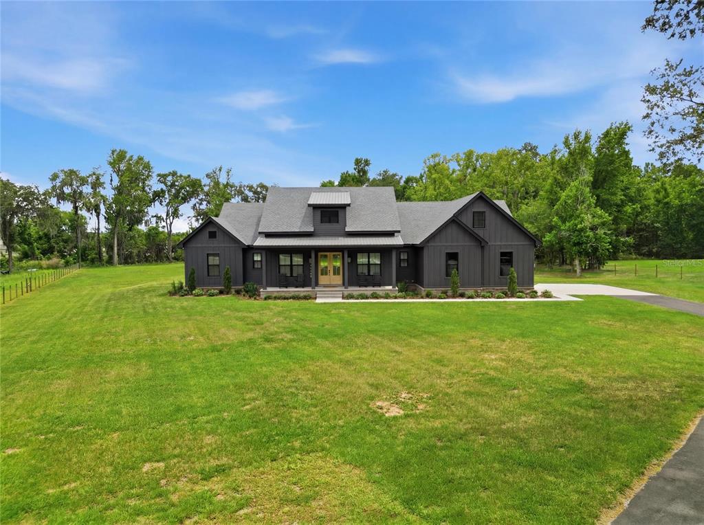 A dark gray farmhouse with a metal roof sits on a large, grassy lot — 2398 GEORGE WHEELER ROAD, LAKELAND, FL