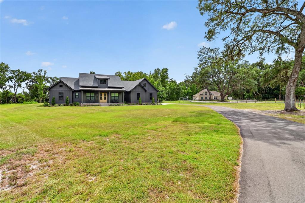 A dark gray modern farmhouse sits on a large grassy lot with a paved driveway — 2398 GEORGE WHEELER ROAD, LAKELAND, FL