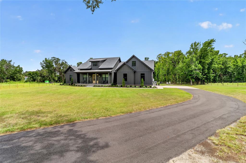 A dark gray farmhouse with a covered porch sits at the end of a paved driveway — 2398 GEORGE WHEELER ROAD, LAKELAND, FL