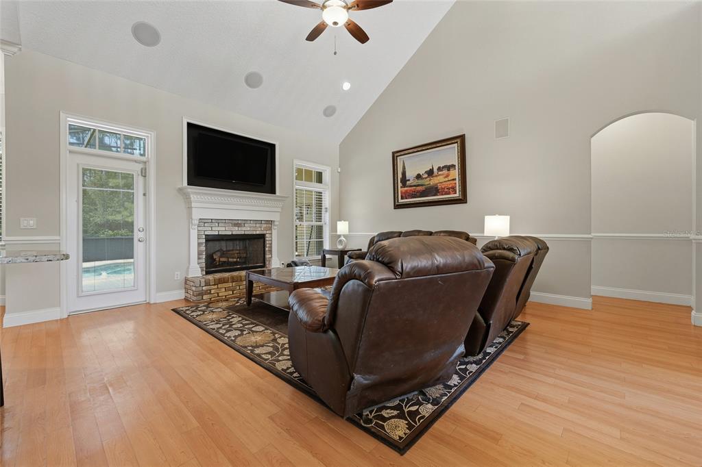 A living room features a brick fireplace, vaulted ceiling, hardwood floors, and leather furniture — 4441 DEER RUN ROAD, ST CLOUD, FL