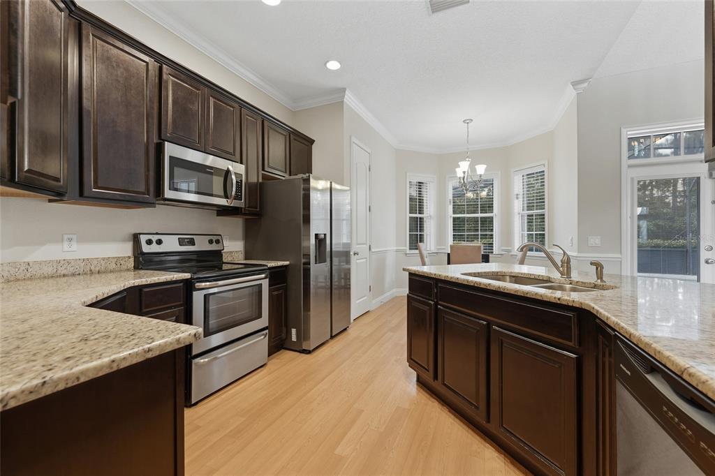A kitchen with dark wood cabinets, granite countertops, stainless steel appliances, and a center island — 4441 DEER RUN ROAD, ST CLOUD, FL