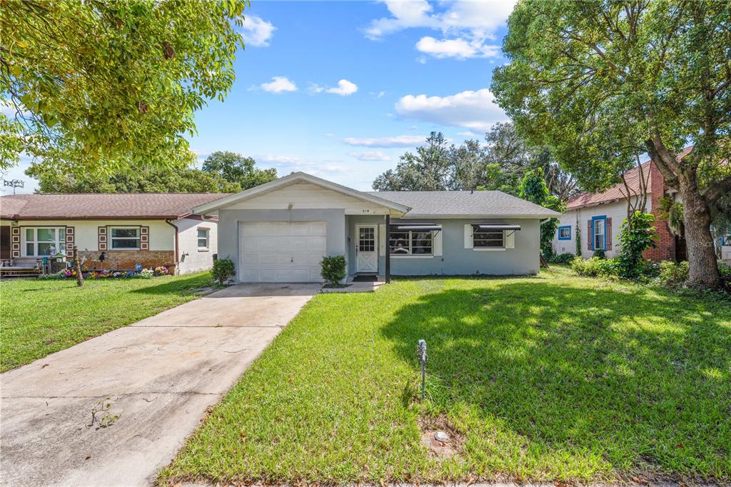 A single-story house with a gray exterior, a front-facing garage, and a concrete driveway — 519 MASSACHUSETTS AVENUE, ST CLOUD, FL