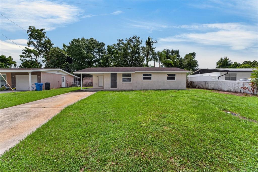 A single-story, light-colored brick house with a front carport and a large grassy yard — 506 SHAMROCK ROAD, BRANDON, FL