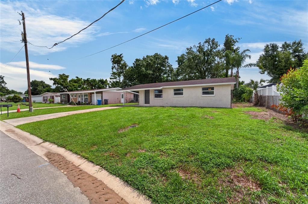 A single-story brick house with a large front lawn and a driveway on a street — 506 SHAMROCK ROAD, BRANDON, FL