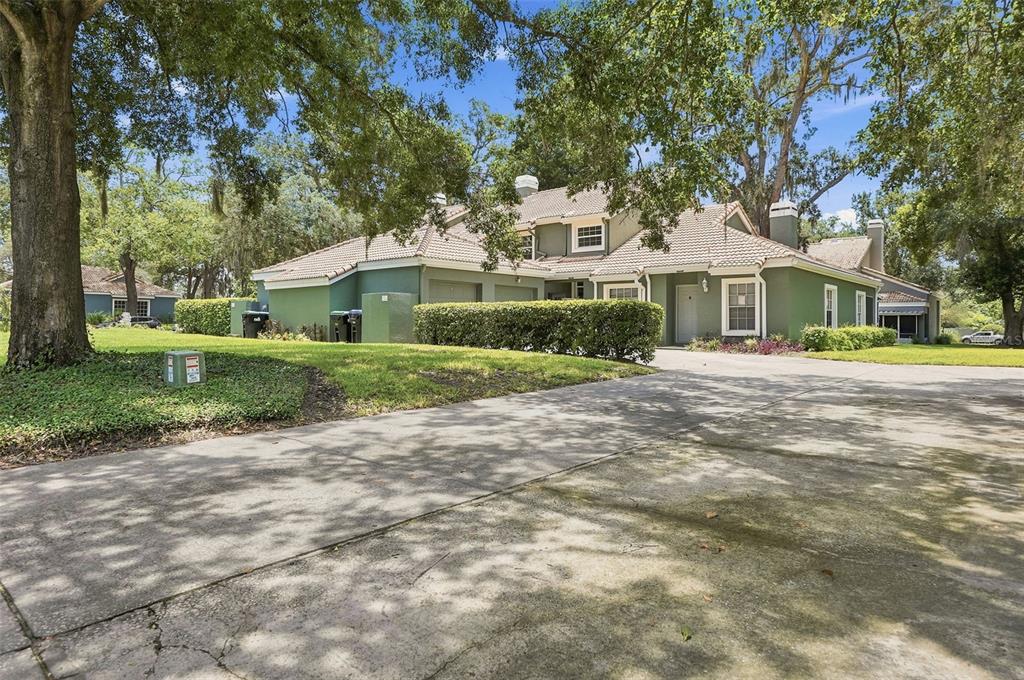 A green two-story house with a tile roof and a concrete driveway under large trees — 4478 OAK ARBOR CIRCLE, ORLANDO, FL