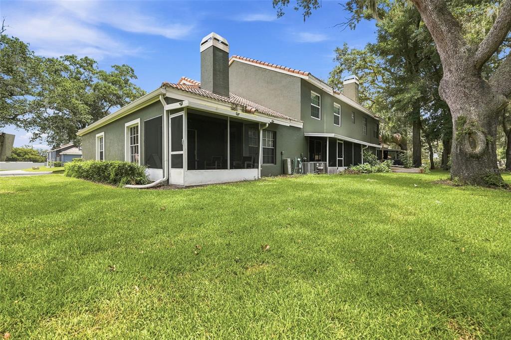 A two-story house with a green exterior, a screened-in porch, and a large oak tree — 4478 OAK ARBOR CIRCLE, ORLANDO, FL