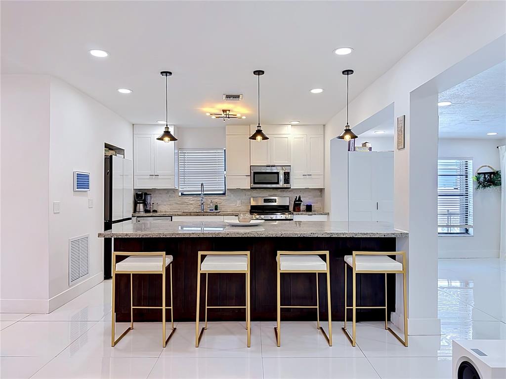 A living room features white sofas, a central coffee table, and a large wall painting — 821 83RD ST, MIAMI BEACH, FL