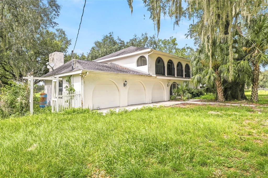A white two-story house with a three-car garage and an upper-level balcony — 8731 LITHIA PINECREST ROAD, LITHIA, FL