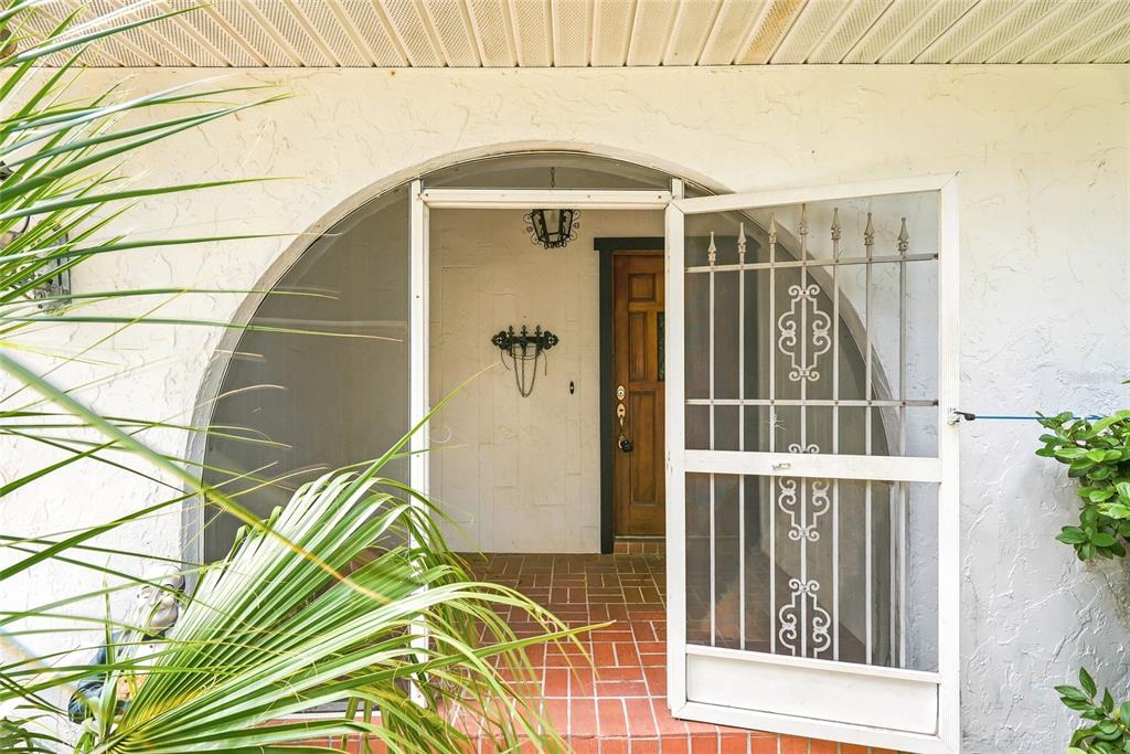 A white arched entryway features a decorative screen door and a wooden front door — 8731 LITHIA PINECREST ROAD, LITHIA, FL