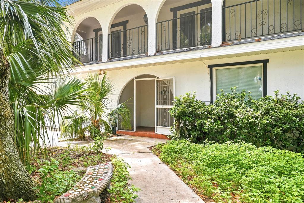 A two-story house exterior features a covered entryway, arched balcony, and a stone walkway — 8731 LITHIA PINECREST ROAD, LITHIA, FL