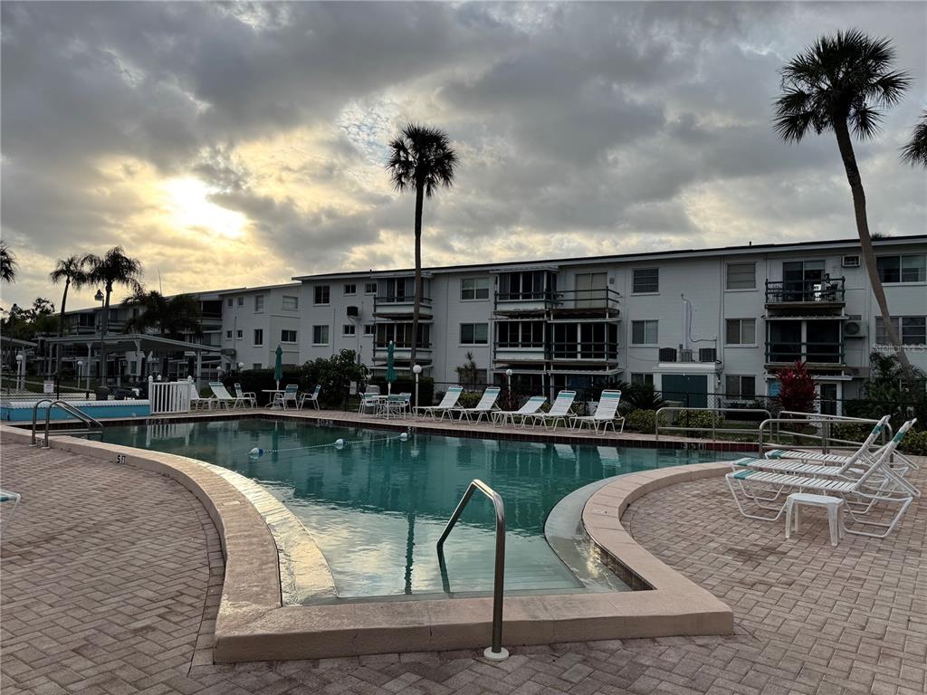 A swimming pool with lounge chairs sits in front of a multi-story apartment building — 1826 SUNNY DRIVE UNIT D26, BRADENTON, FL