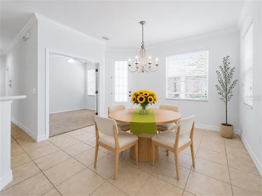 A bright dining area features a round wooden table, four chairs, and a chandelier — 11487 52ND COURT E, PARRISH, FL