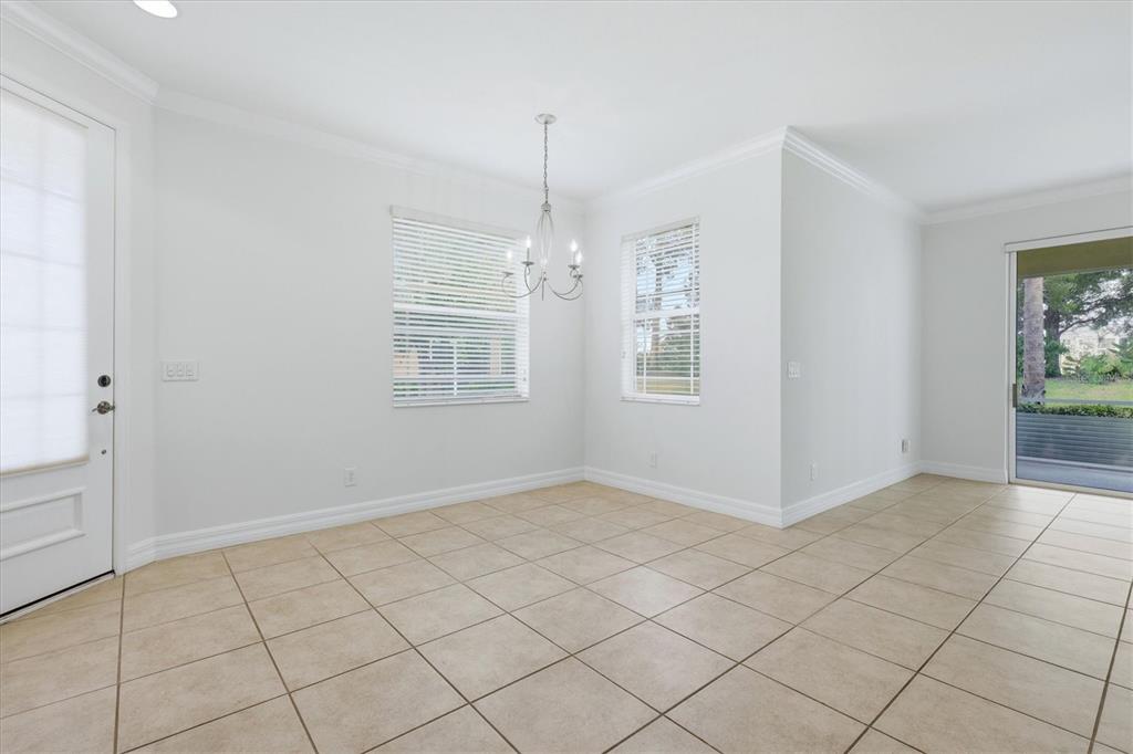 An empty dining area features white walls, tile flooring, a chandelier, and sliding glass doors — 11487 52ND COURT E, PARRISH, FL