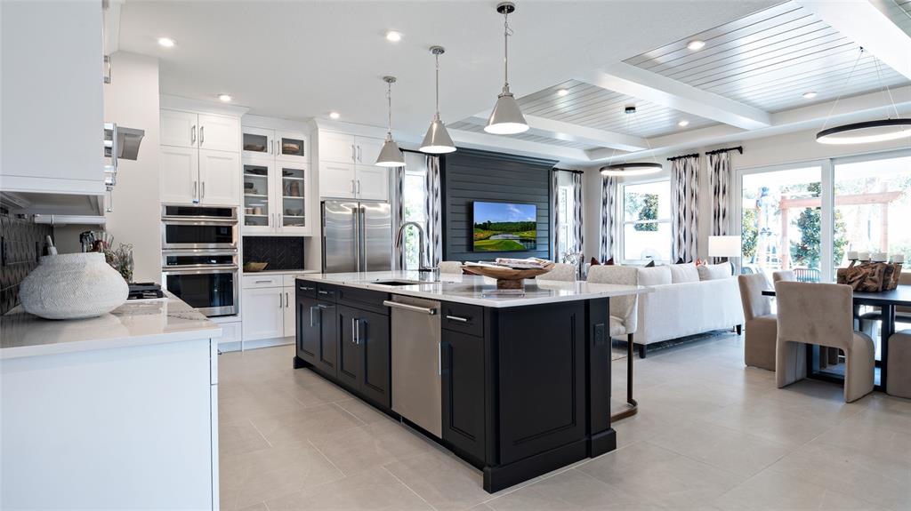 A modern kitchen features a dark island, white cabinetry, and an open-concept living area — 1732 POINT GRACE ROAD, TAVARES, FL