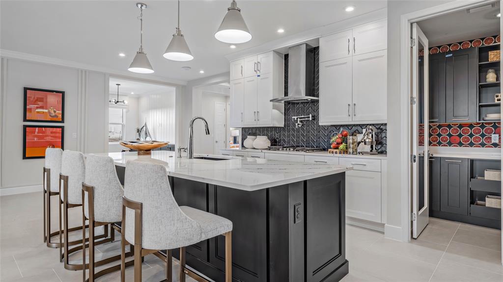 A modern kitchen features a black island with white countertops, white cabinetry, and a pantry — 1732 POINT GRACE ROAD, TAVARES, FL