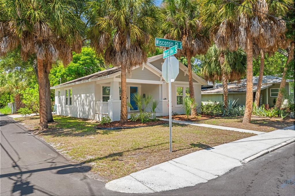 A single-story house with a blue front door sits on a corner lot with palms — 325 WISCONSIN COURT S, ST PETERSBURG, FL