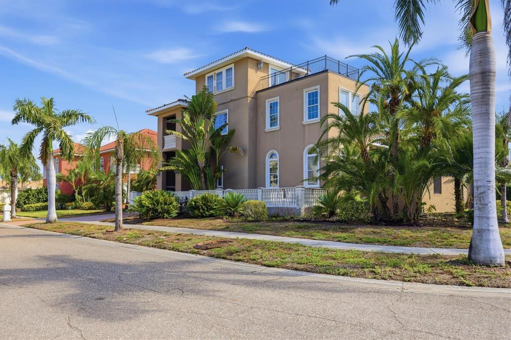 A three-story tan stucco house with a rooftop terrace and palm trees in the front — 1304 JUMANA LOOP, APOLLO BEACH, FL