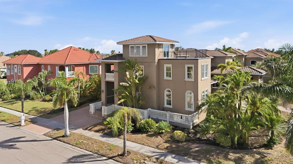 An exterior view of a multi-story tan house with a balcony and surrounding palm trees — 1304 JUMANA LOOP, APOLLO BEACH, FL