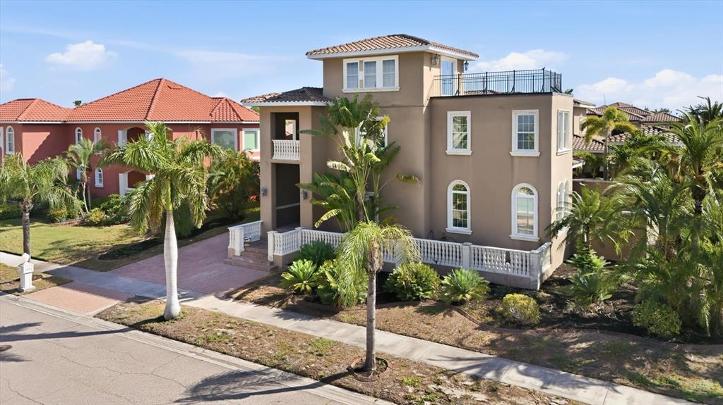 A three-story tan stucco house with a flat roof terrace and palm trees in front — 1304 JUMANA LOOP, APOLLO BEACH, FL