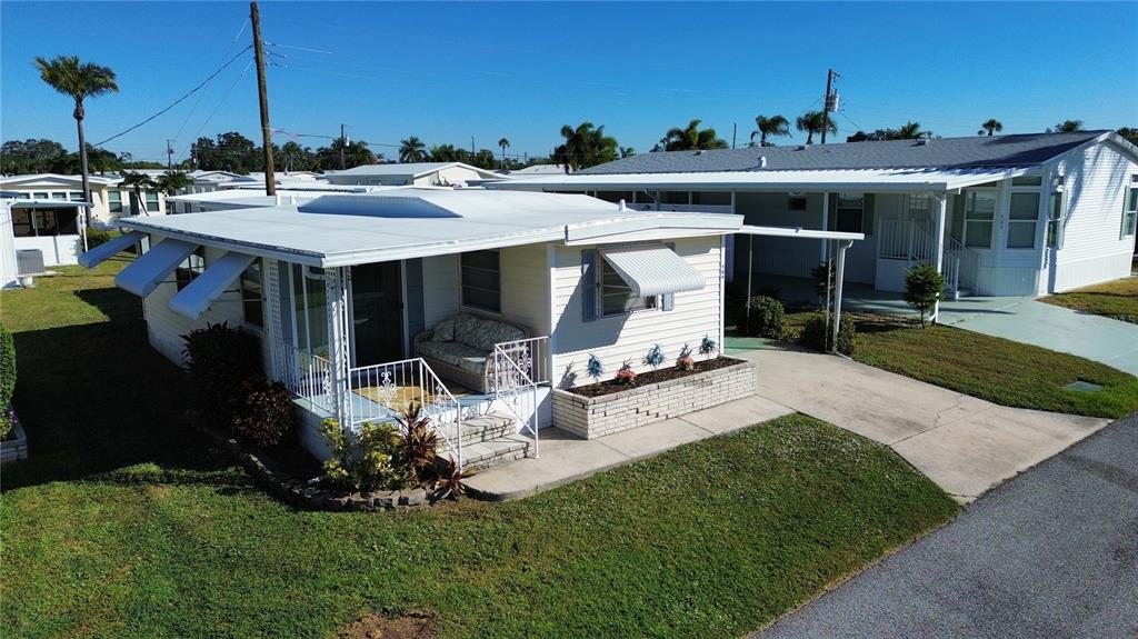 An exterior view of a single-story mobile home with a white porch and metal awnings — 504 49TH C AVENUE DRIVE E, BRADENTON, FL