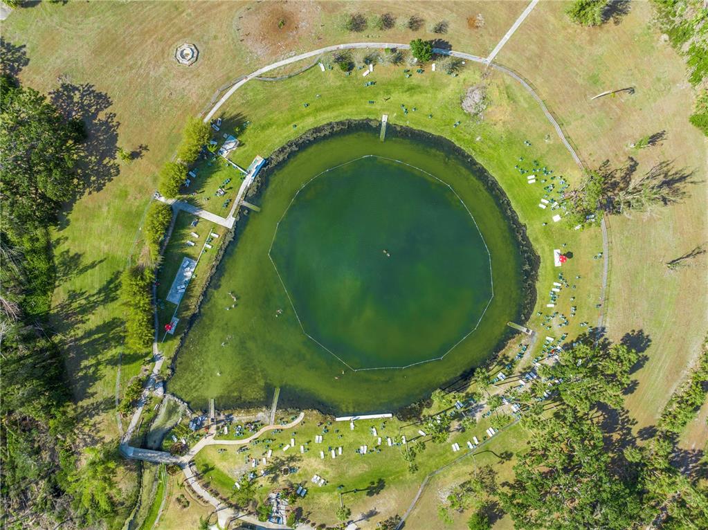 An aerial view shows a circular swimming lake surrounded by a grassy park and trees — LOTS 19 & 20 SABRINA TERRACE, NORTH PORT, FL