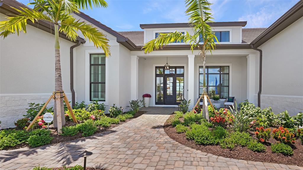 A paved walkway leads to the front entrance of a house with palm trees — 11433 BRIGHTLY DRIVE, VENICE, FL