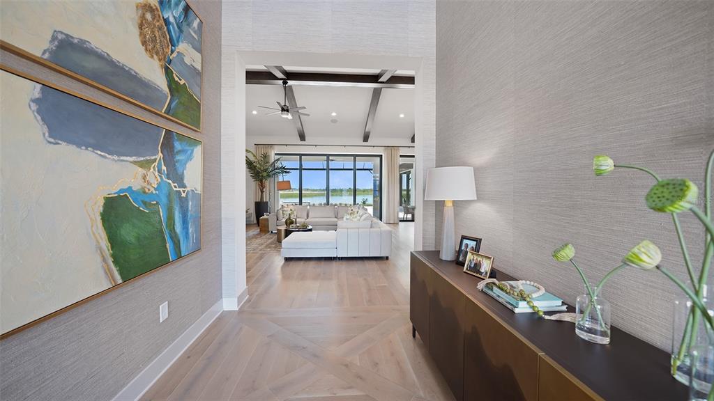 A foyer with textured wallpaper and wood floors leads into a living room with lake views — 11433 BRIGHTLY DRIVE, VENICE, FL