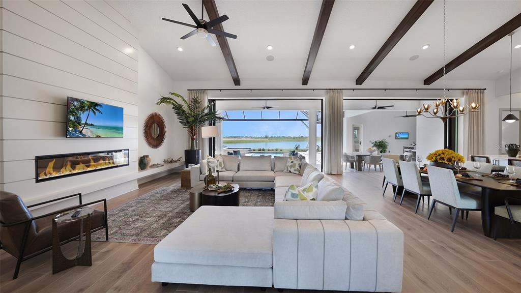 A spacious open-concept living and dining area features vaulted ceilings, exposed beams, and a fireplace — 11433 BRIGHTLY DRIVE, VENICE, FL